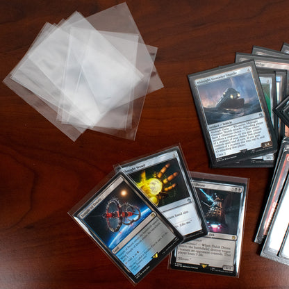 Collection of trading cards on a wooden surface with protective sleeves.